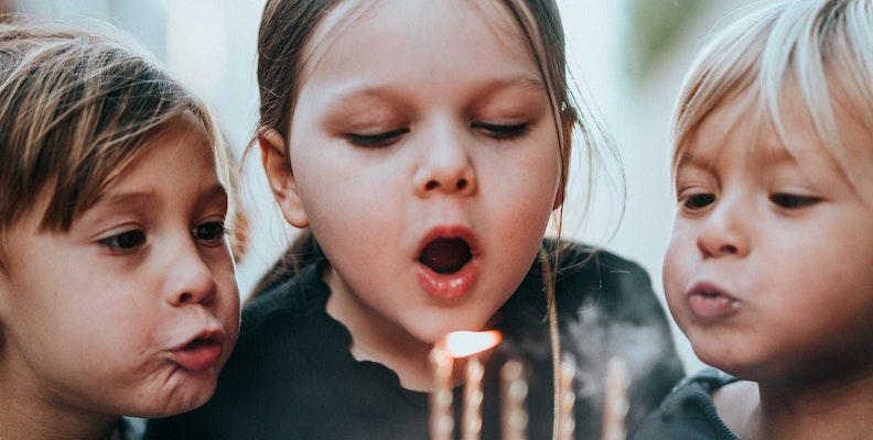 Barn blåser ljusen på födelsedagstårtan.